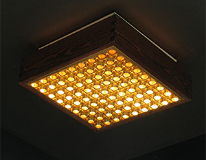Wooden ceiling lamp illuminated behind grating Wabbes