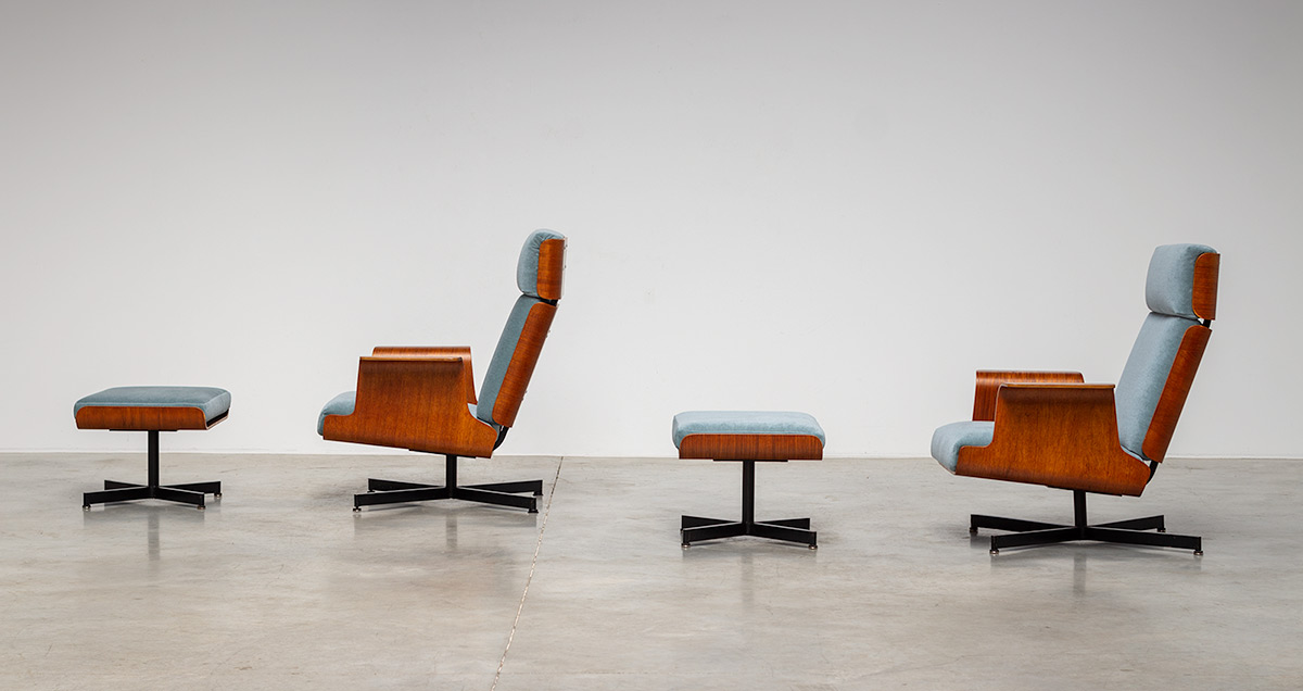 Pair of stunning and rare lounge chairs with matching ottoman, circa 1960s. These smooth and sculptural chairs are made of moulded teak plywood shells. The starbase is build from a black lacquered steel. The design truly embody the spirit of the mid-century, but still conserve their modernity. The chairs are new upholstered in blue-grey velvet.